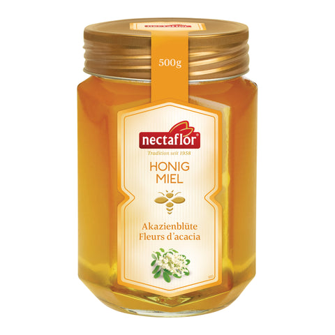 Sechseckiges Honigglas mit Goldenem Metaldeckel und gelben Flüssigen Honig und einem Gelben 'Akazienhonig' Etikett