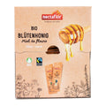 Verpackung mit dem Schriftzug 'nectaflor Tradition seit 1958' und 'BIO BLÜTENHONIG Miel de fleurs flüssig' sowie zwei Honigtüten und einer Honiglöffel-Illustration mit tropfendem Honig