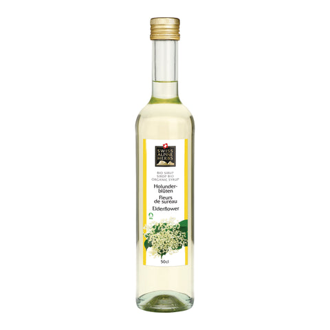 Schmale Glasflasche mit goldfarbenem Schraubverschluss, gefüllt mit hellem Sirup. Auf dem Etikett steht „Holunderblüten / Fleurs de sureau / Elderflower“ unter dem Swiss Alpine Herbs Logo. Unten sind weisse Holunderblüten abgebildet, die Füllmenge beträgt 50 cl.