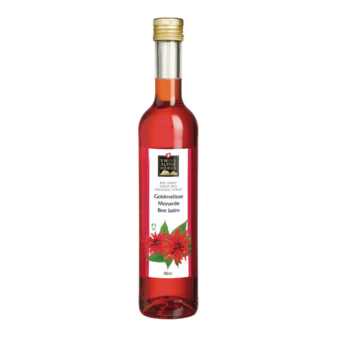 Hohe Glasflasche mit goldfarbenem Schraubverschluss und rotem Sirup, Etikett mit der Aufschrift 'SWISS ALPINE HERBS BIO SIRUP SIRUP BIO ORGANIC SYRUP Goldmelisse Monarde Bee balm' und einer Abbildung roter Blüten