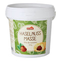 Weißer Kunststoffbecher mit grünem Etikett und Aufschrift 'Haselnuss Masse' sowie Abbildung von Haselnuss und Gebäck