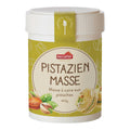 Weißer Eimer mit grünem Etikett und der Aufschrift 'PISTAZIEN MASSE' sowie Abbildungen von Pistazien und Macarons
