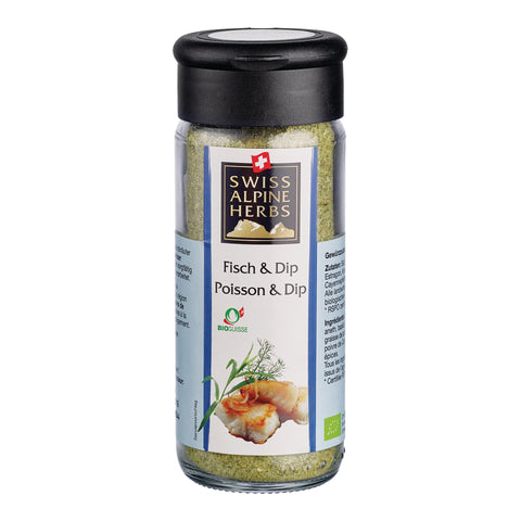 Transparente Gewürzmühle mit schwarzem Deckel. Auf dem Etikett steht „Fisch & Dip / Poisson & Dip“ unter dem Swiss Alpine Herbs Logo. Im Glas ist eine grünliche Gewürzmischung sichtbar. Unten sind Fischstücke, grüne Kräuter sowie das Bio-Suisse-Logo abgebildet.