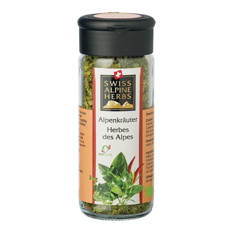Transparente Gewürzmühle mit schwarzem Deckel. Auf dem Etikett steht „Alpenkräuter / Herbes des Alpes“ unter dem Swiss Alpine Herbs Logo. Im Glas sind grüne Kräuter sichtbar. Unten sind grüne Kräuter, rote Chilischoten sowie das Bio-Suisse-Logo abgebildet.