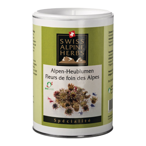 Weisse Dose mit hellgrünem Etikett. In der Mitte steht „Alpen-Heublumen / Fleurs de foin des Alpes“ unter dem Swiss Alpine Herbs Logo. Unten ist eine Abbildung von getrockneten Blumen und Blüten sowie das Bio-Suisse-Logo zu sehen.