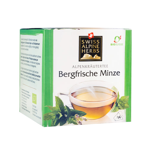 Grüne Verpackung mit der Aufschrift 'Swiss Alpine Herbs Alpenkräutertee Bergfrische Minze' und einem Teeglas mit Minzblättern