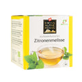 Packung mit Zitronenmelisse-Alpenkräutertee der Marke Swiss Alpine Herbs mit Teetasse und Zitronenmelisseblättern