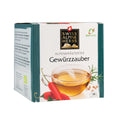 Verpackung eines Kräutertees der Marke Swiss Alpine Herbs mit der Aufschrift 'Alpenkräutertee Gewürzzauber' und Abbildungen von Chili, Minze und Rosmarin