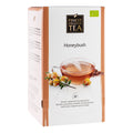 Verpackung des Honeybush-Tees von Finest Organic Tea. Weiße Teeschachtel mit beigefarbenen Akzenten, Abbildung einer Tasse Honeybush-Tee, Honeybush-Blüten und 24 einzeln verpackten Pyramidenbeuteln.