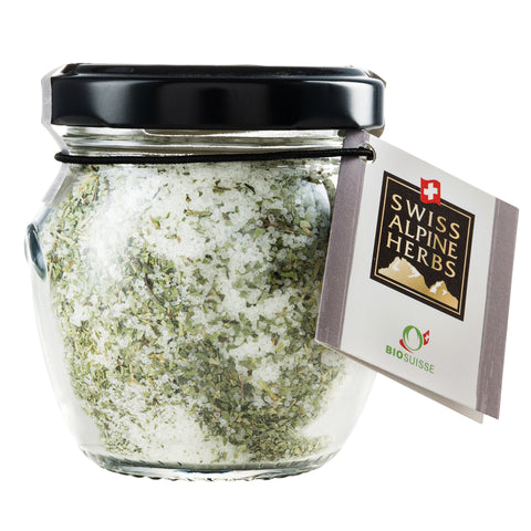 Glas mit grünem Kräutersalz und Etikett „Swiss Alpine Herbs“.